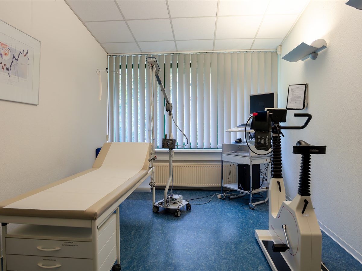 Untersuchungsraum mit Liege, EKG-Gerät und Ergometer