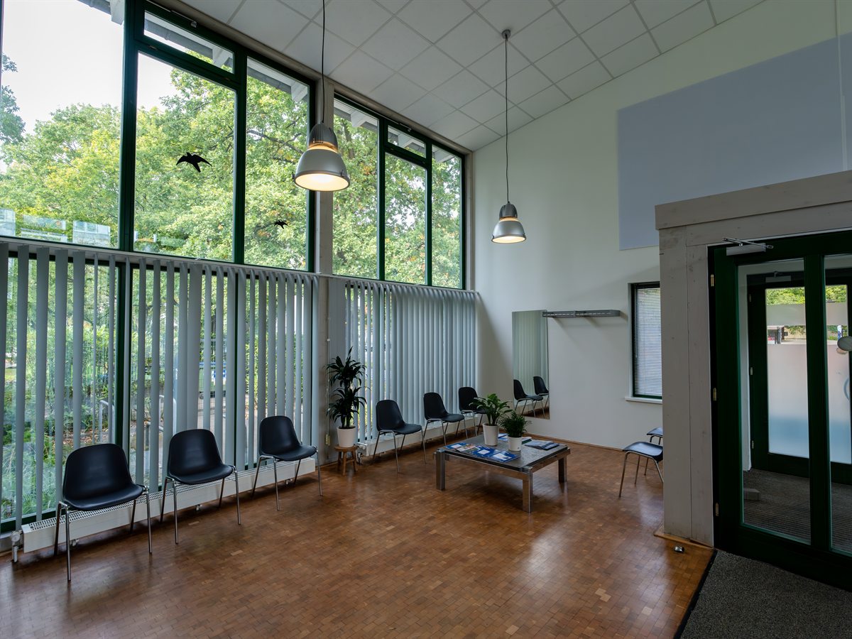 Wartezimmer mit großer Fensterfront zum Grünen